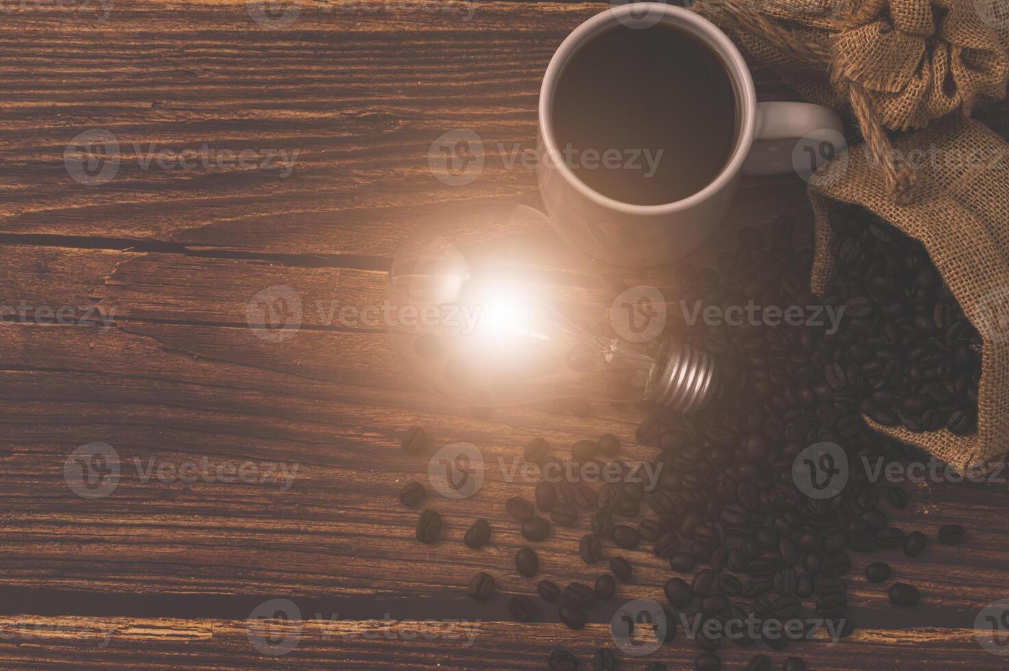 Kaffeetasse und eine Glühbirne, die Energie auf einem Holztisch abgibt foto