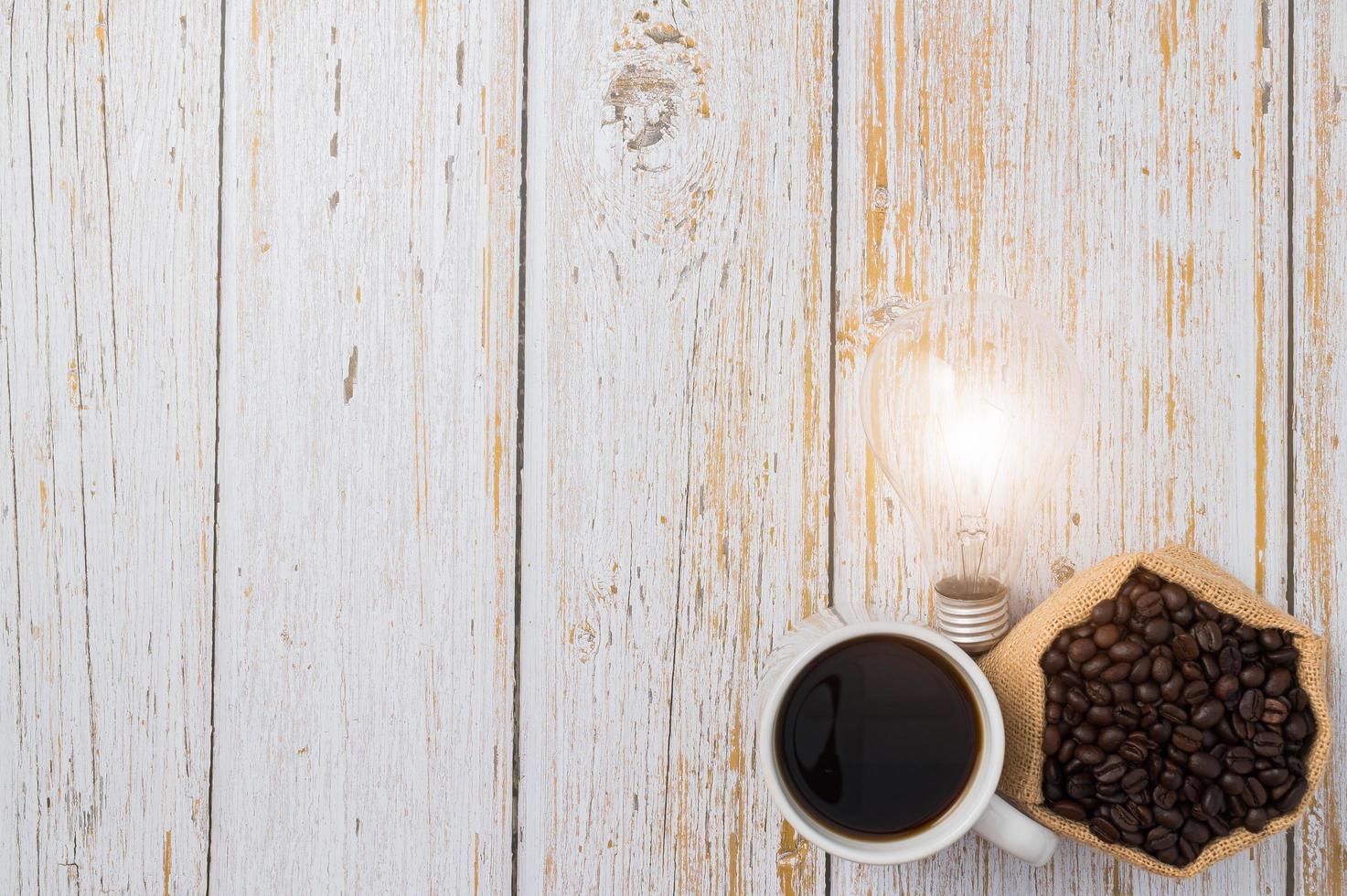 Kaffeetasse und eine Glühbirne, die Energie auf einem Holztisch abgibt foto