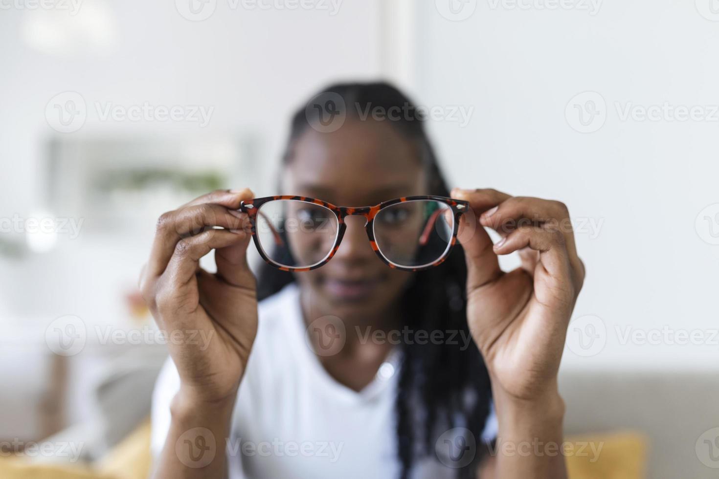 jung afrikanisch Frau hält Brille mit Dioptrie Linsen und sieht aus durch ihnen, das Problem von Kurzsichtigkeit, Vision Korrektur foto