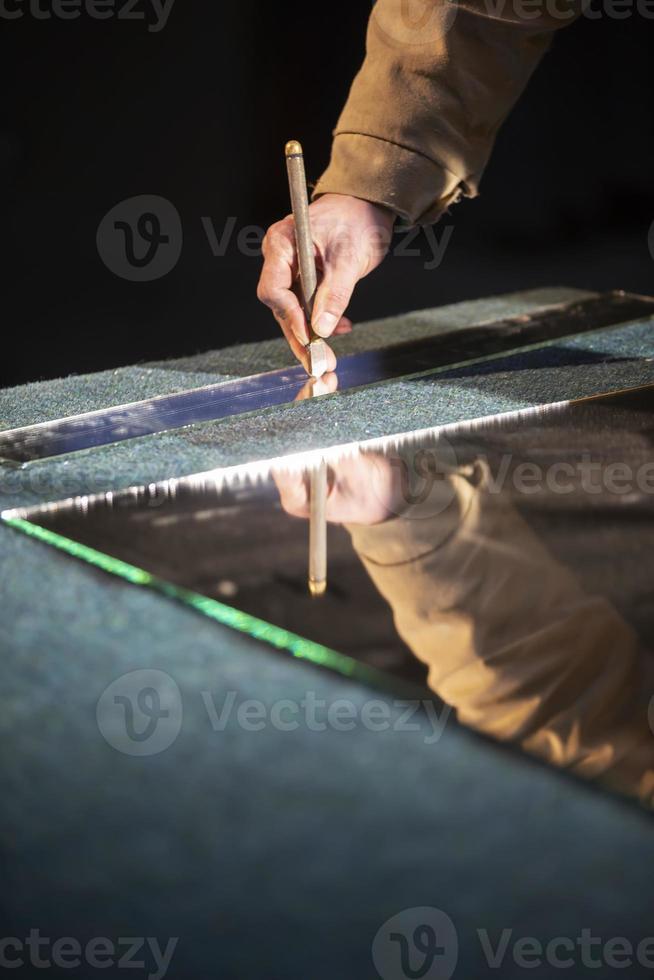 das Hand von ein Arbeiten Mann schneidet ein Spiegel mit ein Glas Cutter. foto