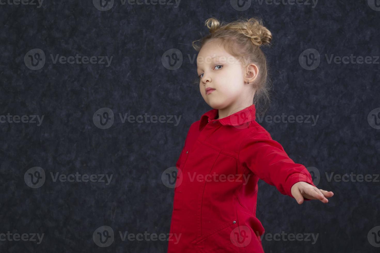 schön wenig Mädchen im ein rot Kleid erstreckt sich aus ihr Hand. foto