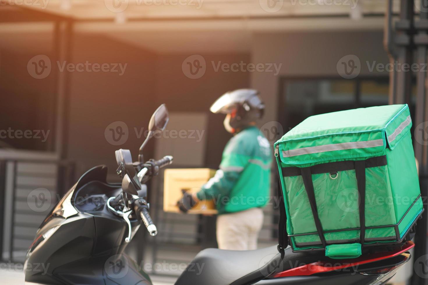 Grün Fahrer Paket Lieferung Mann von ein Paket durch ein Bedienung senden zu heim. Hand halten Sendungen und Einreichung Kunde akzeptieren ein von Kasten. foto