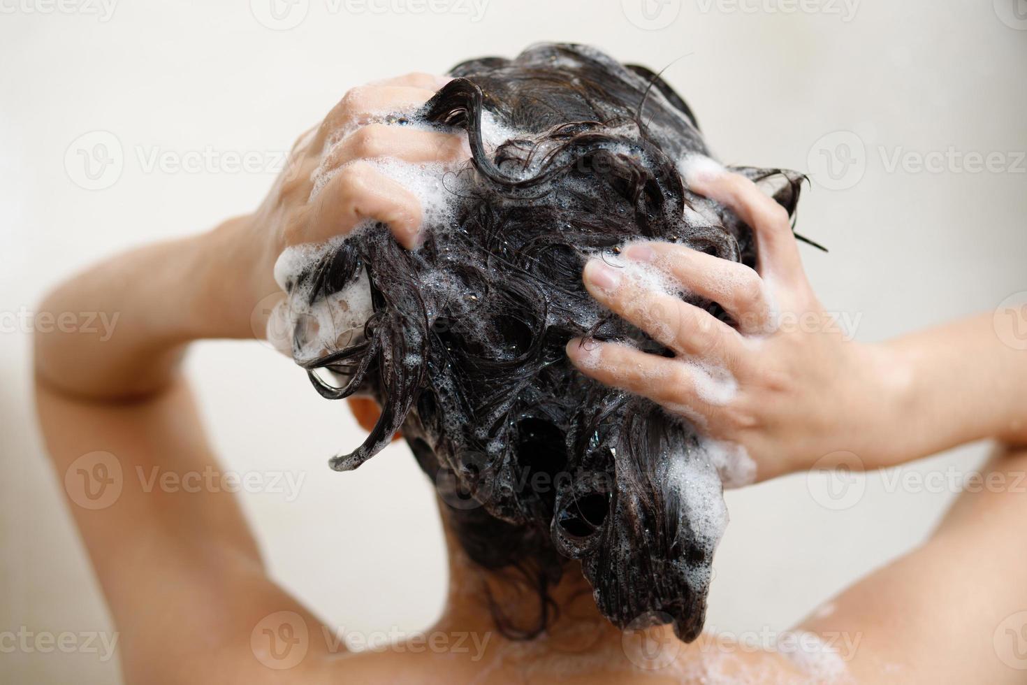 Frau nehmen Dusche und Waschen Haar mit Shampoo im Badezimmer beim Zuhause foto