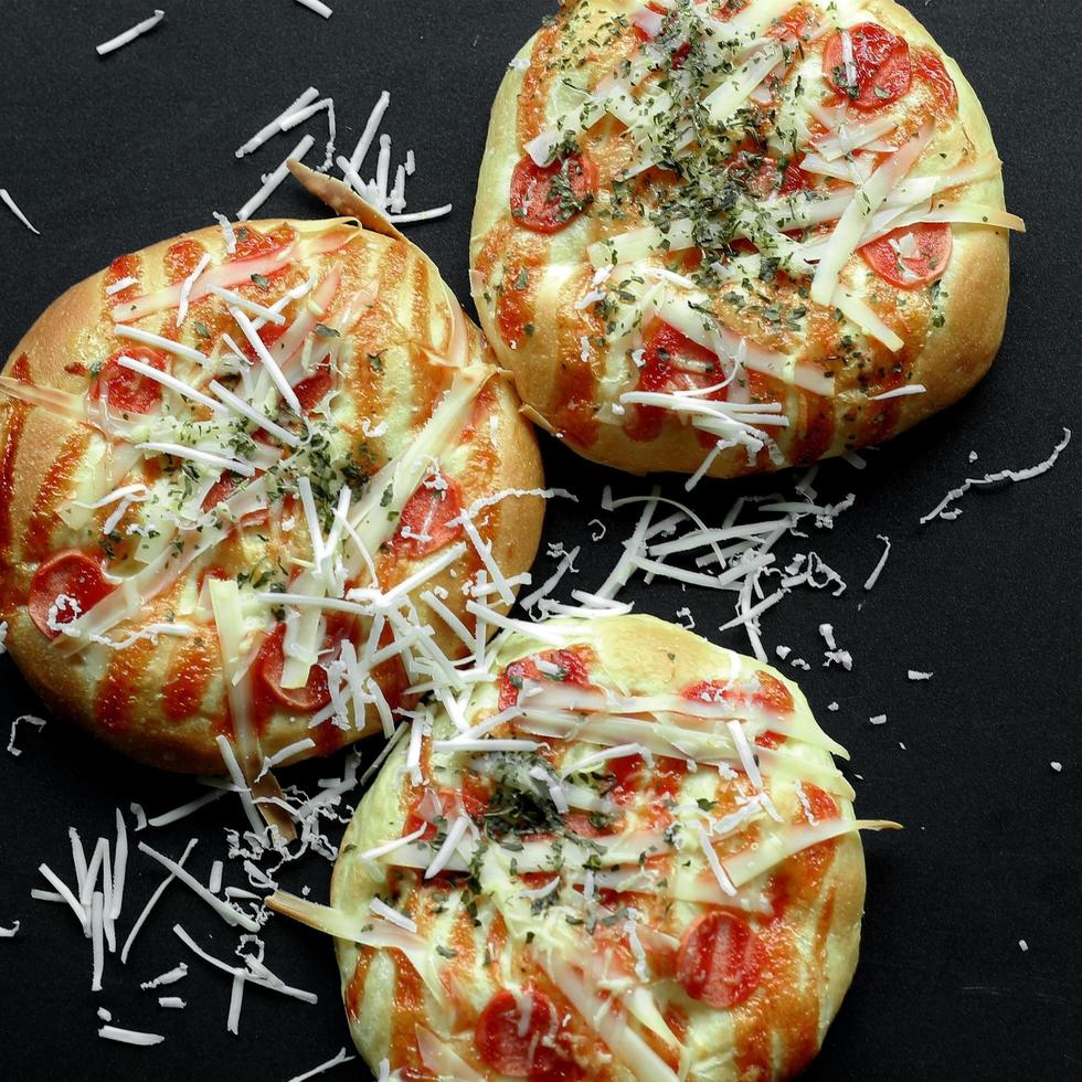 Mini Pizza gekrönt mit gerieben Käse und etwas Fleisch foto