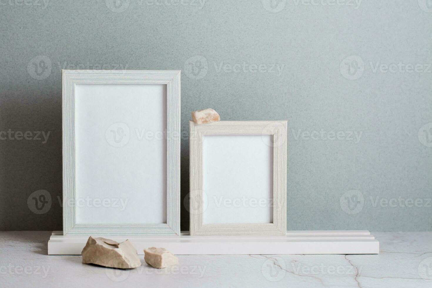 Öko freundlich Zuhause Dekor zwei Foto Frames und Steine auf das Tabelle auf ein grau Hintergrund. Pastell- Schatten