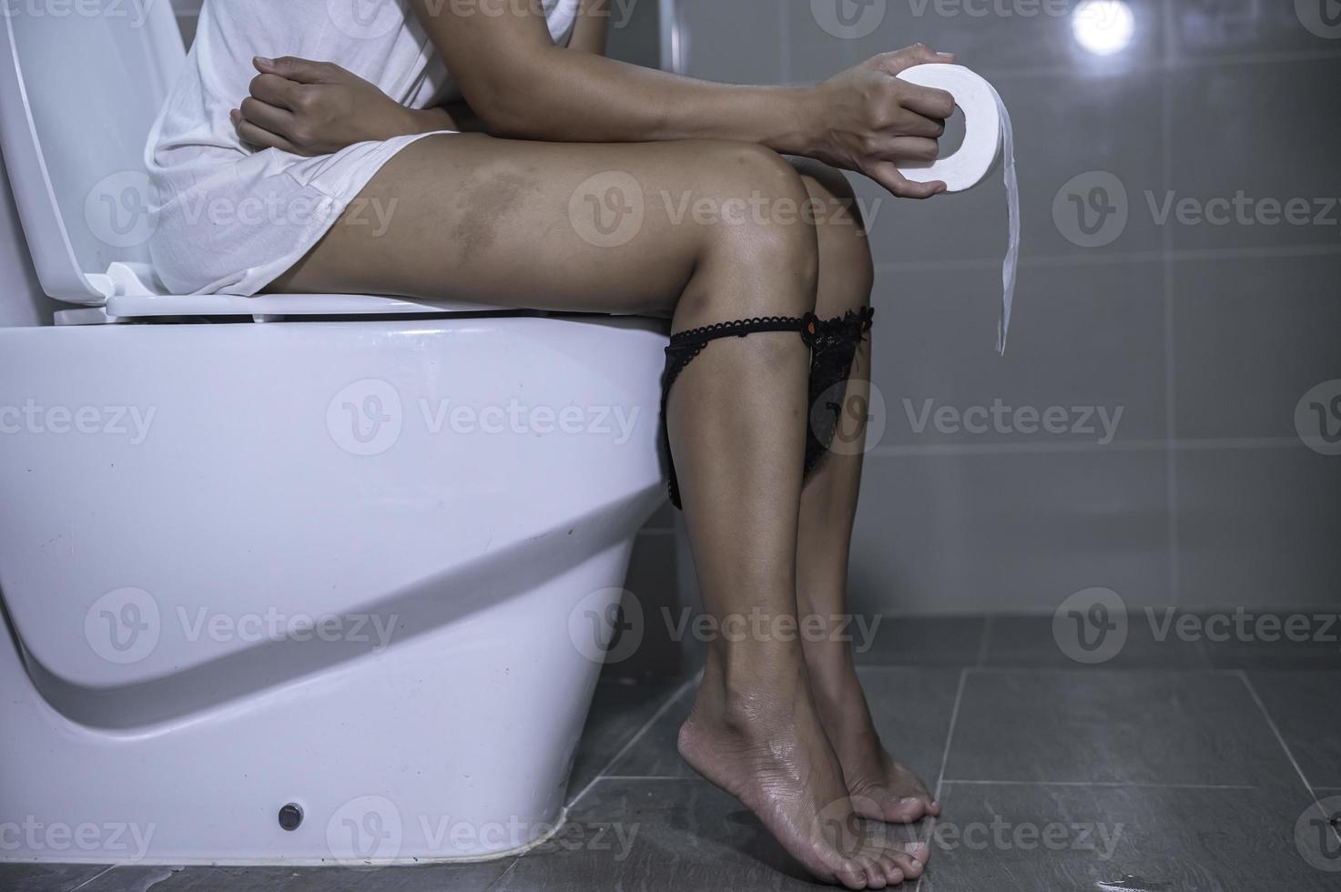 haben Probleme mit Ausscheidung Konzept, ein asiatisch Frau sitzt auf das Toilette Schüssel, Verstopfung und ein lange Zeit im das Toilette. foto