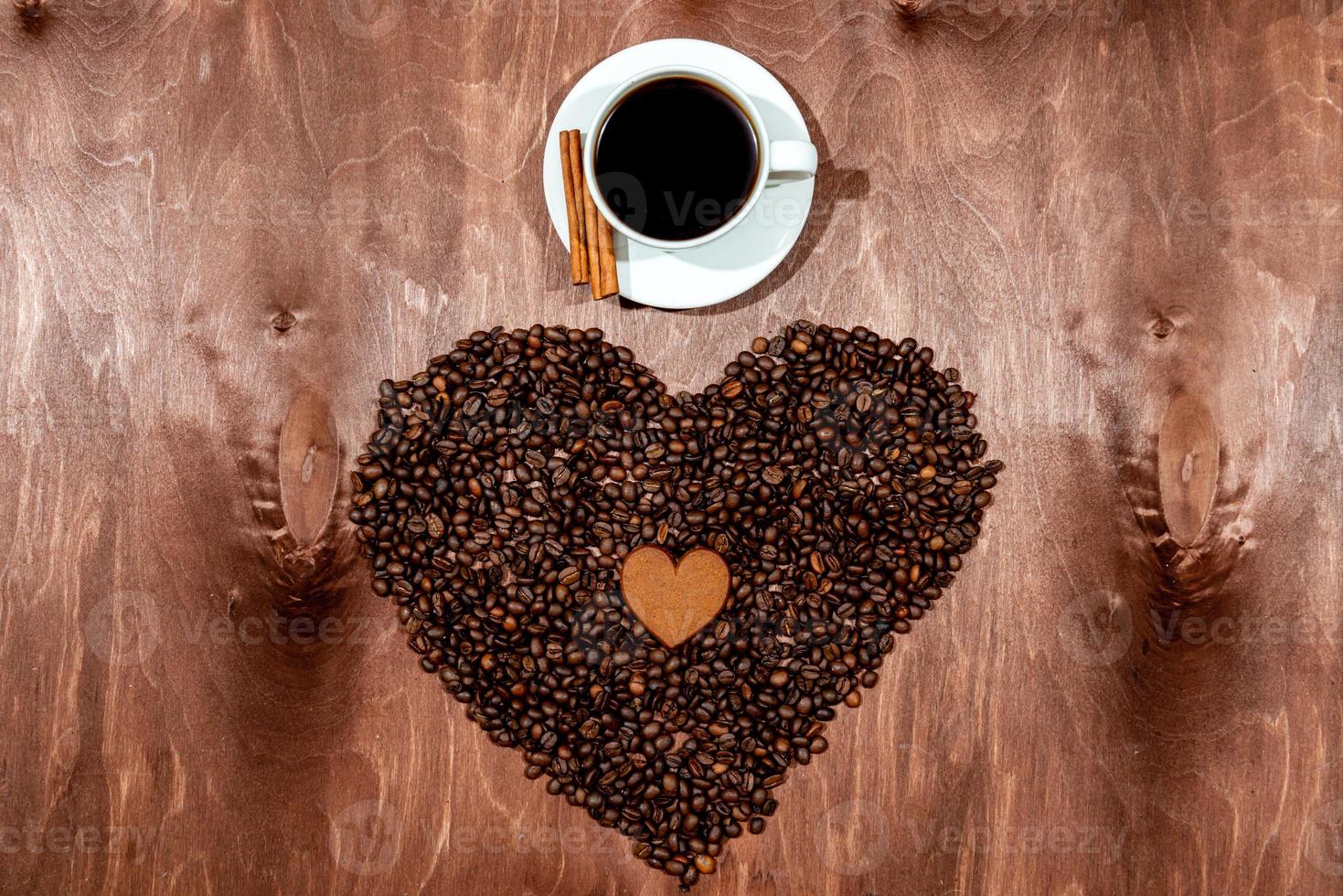 weiße Kaffeetasse, Lebkuchen und Kaffeebohnenherz auf einem hölzernen Texturbrett foto