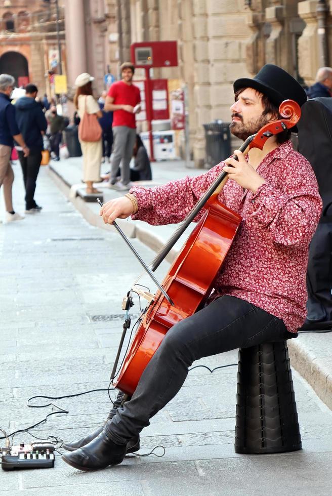 Bologna, Italien, April 16, 2022, Straße Künstler, spielen Cello im das historisch Innenstadt Kreis von Bologna. Busking auf Straße Konzept. foto