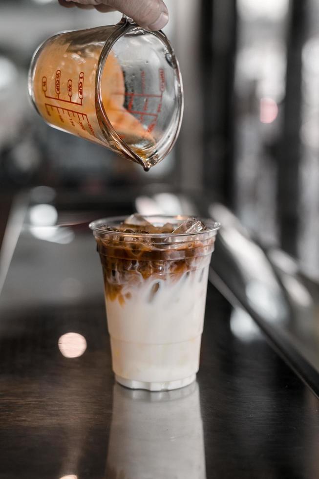 Barista gießt Espresso in ein Glas Eiskaffee foto