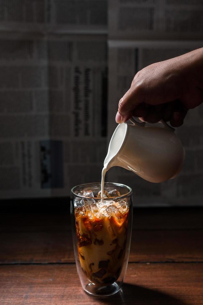 Barista gießt Milch in ein Glas Eiskaffee foto