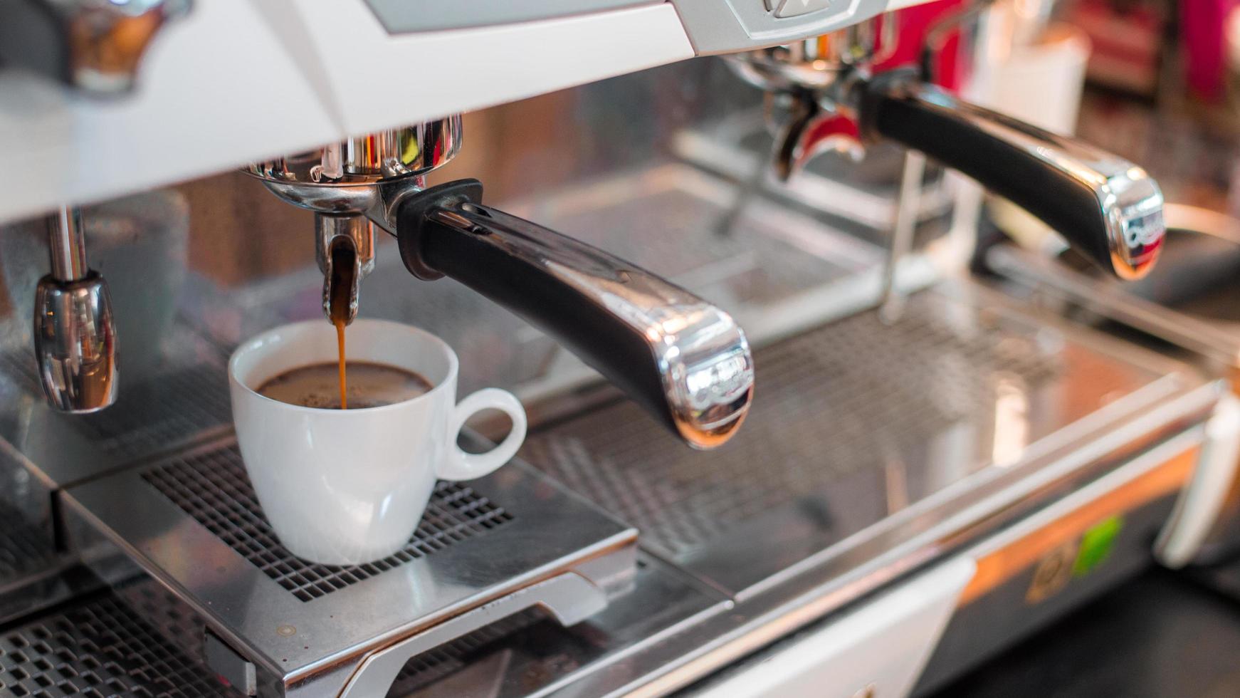 schwarzer Espressokaffee tropft von der Maschine foto
