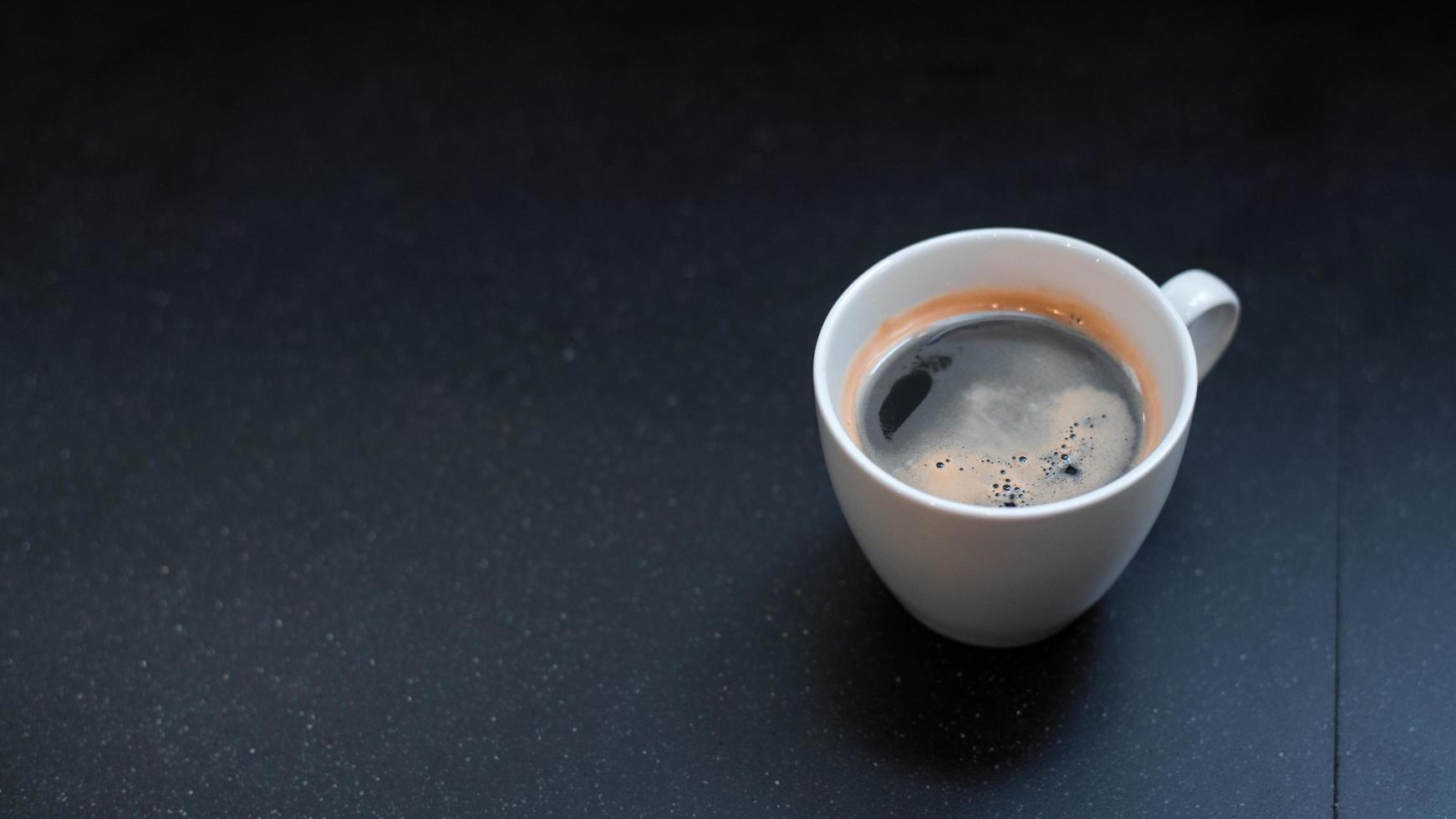 schwarzer Kaffee auf einem dunklen Tisch foto