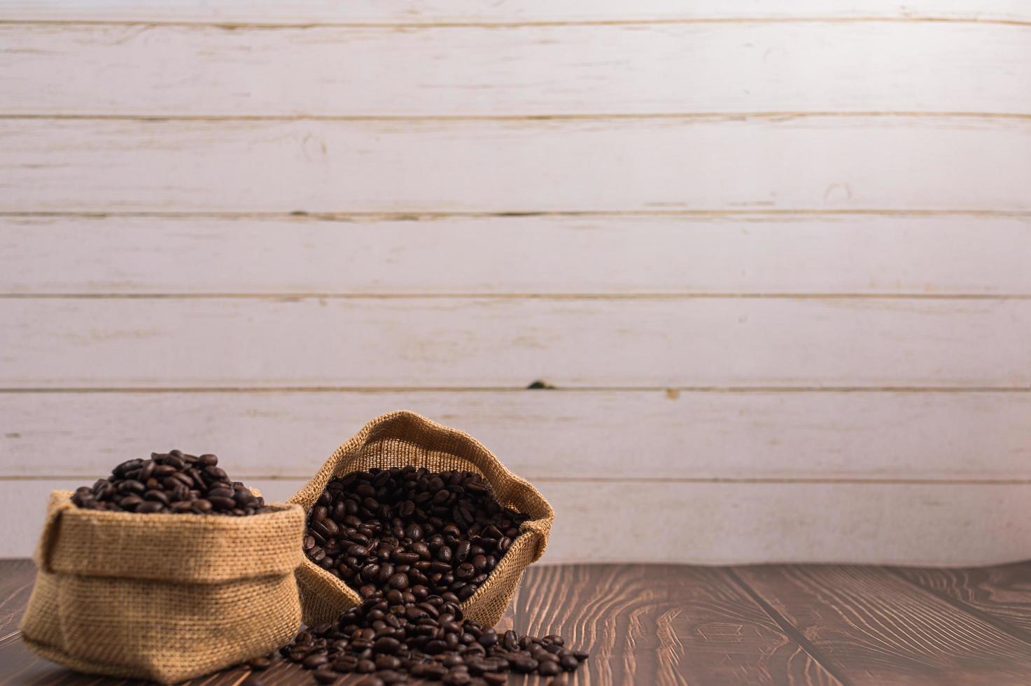 Taschen mit Kaffeebohnen auf einem Holztisch foto