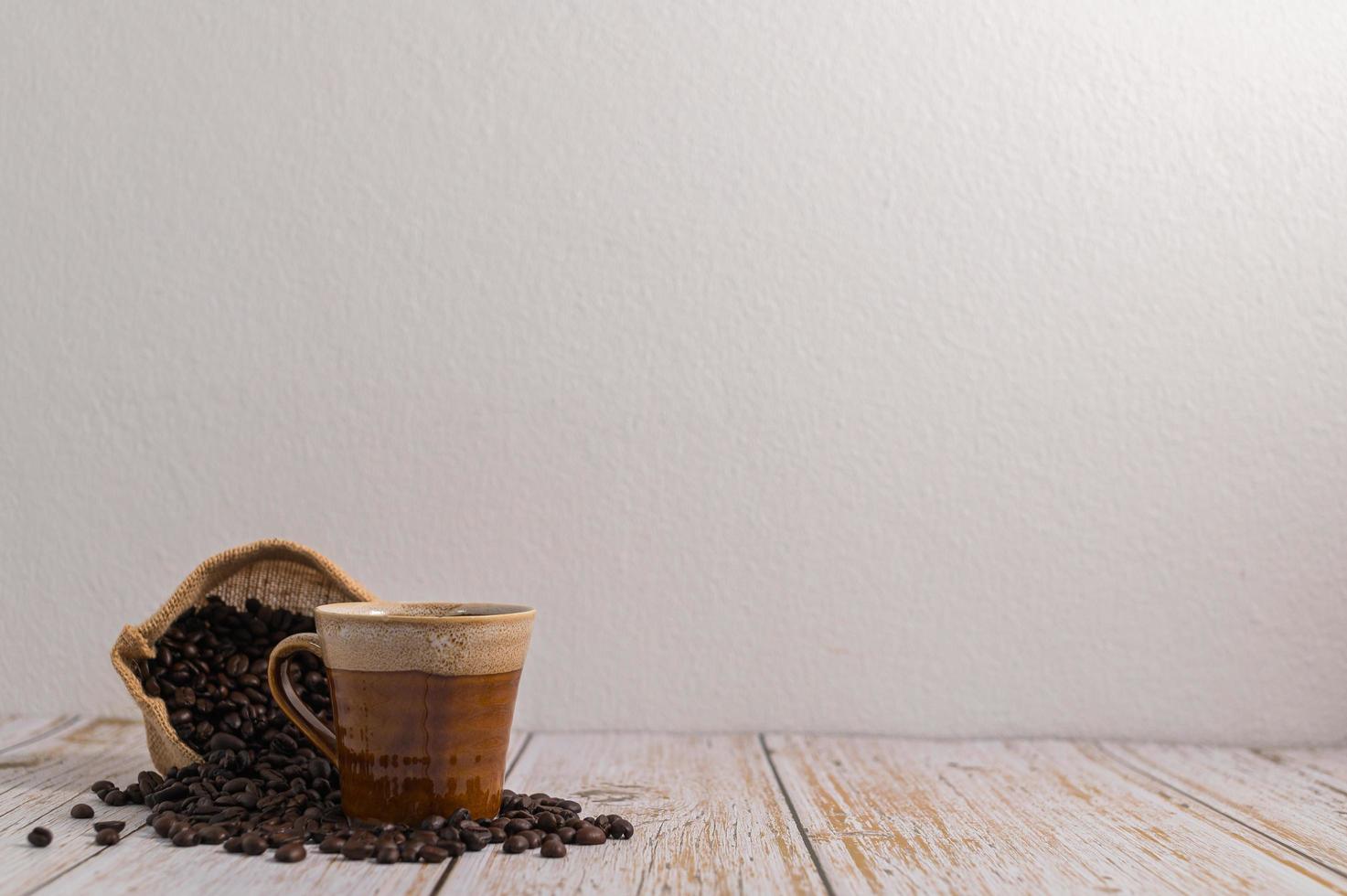 eine Kaffeetasse und eine Tüte Kaffeebohnen auf einem Holztisch foto