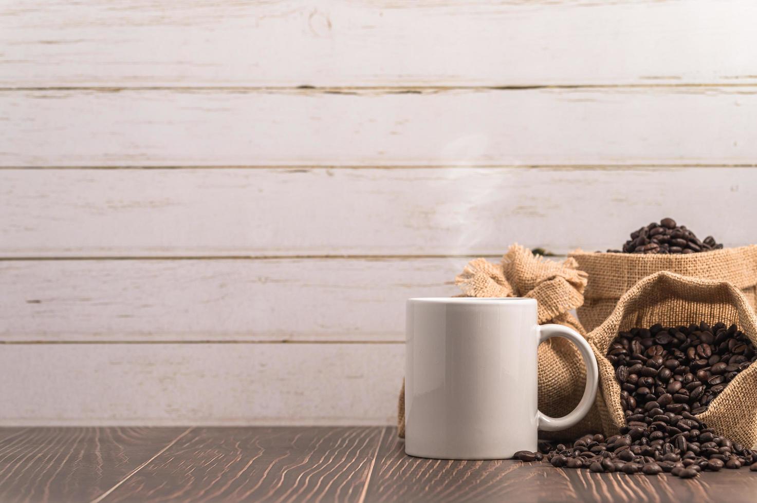 eine Kaffeetasse und Taschen mit Kaffeebohnen auf einem Holztisch foto