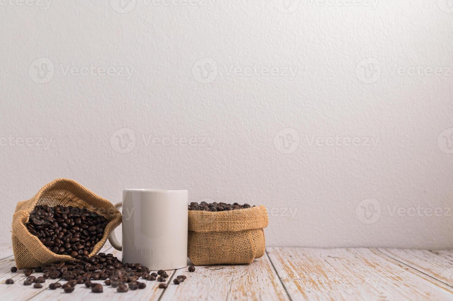 eine Kaffeetasse und Taschen mit Kaffeebohnen auf einem Holztisch foto