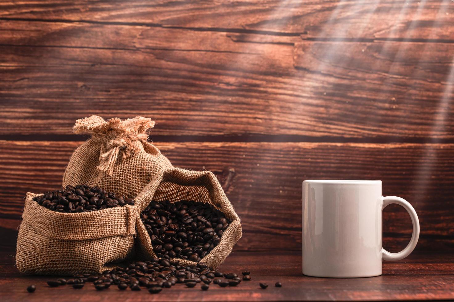 eine Kaffeetasse und Taschen mit Kaffeebohnen auf einem Holztisch foto