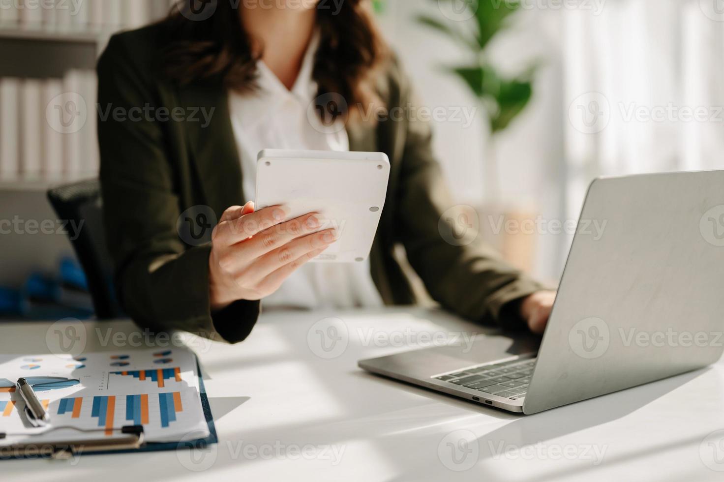 Frauen zählen Münzen auf dem Taschenrechner aus dem Sparschwein. Hand, die einen Stift hält, der an einem Taschenrechner arbeitet, um auf dem Schreibtisch die Kosten im Heimbüro zu berechnen. foto
