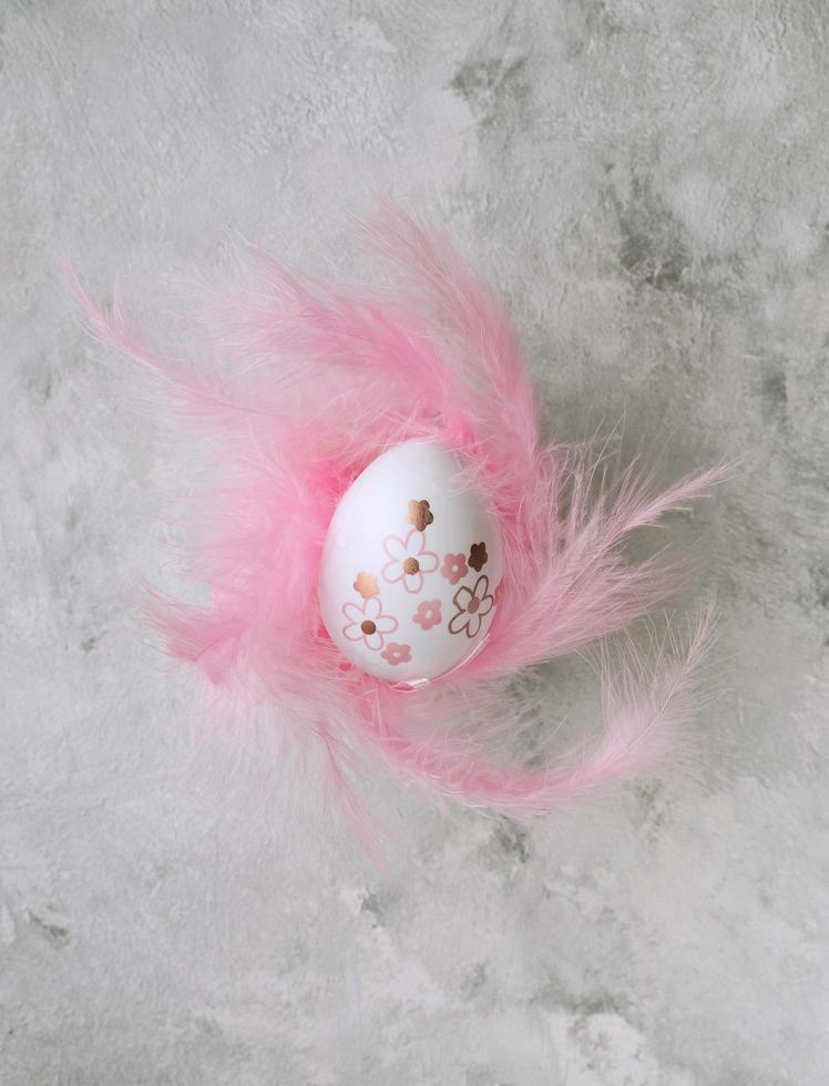 Ostern malte Eier und rosa Federn auf einem Marmorhintergrund foto