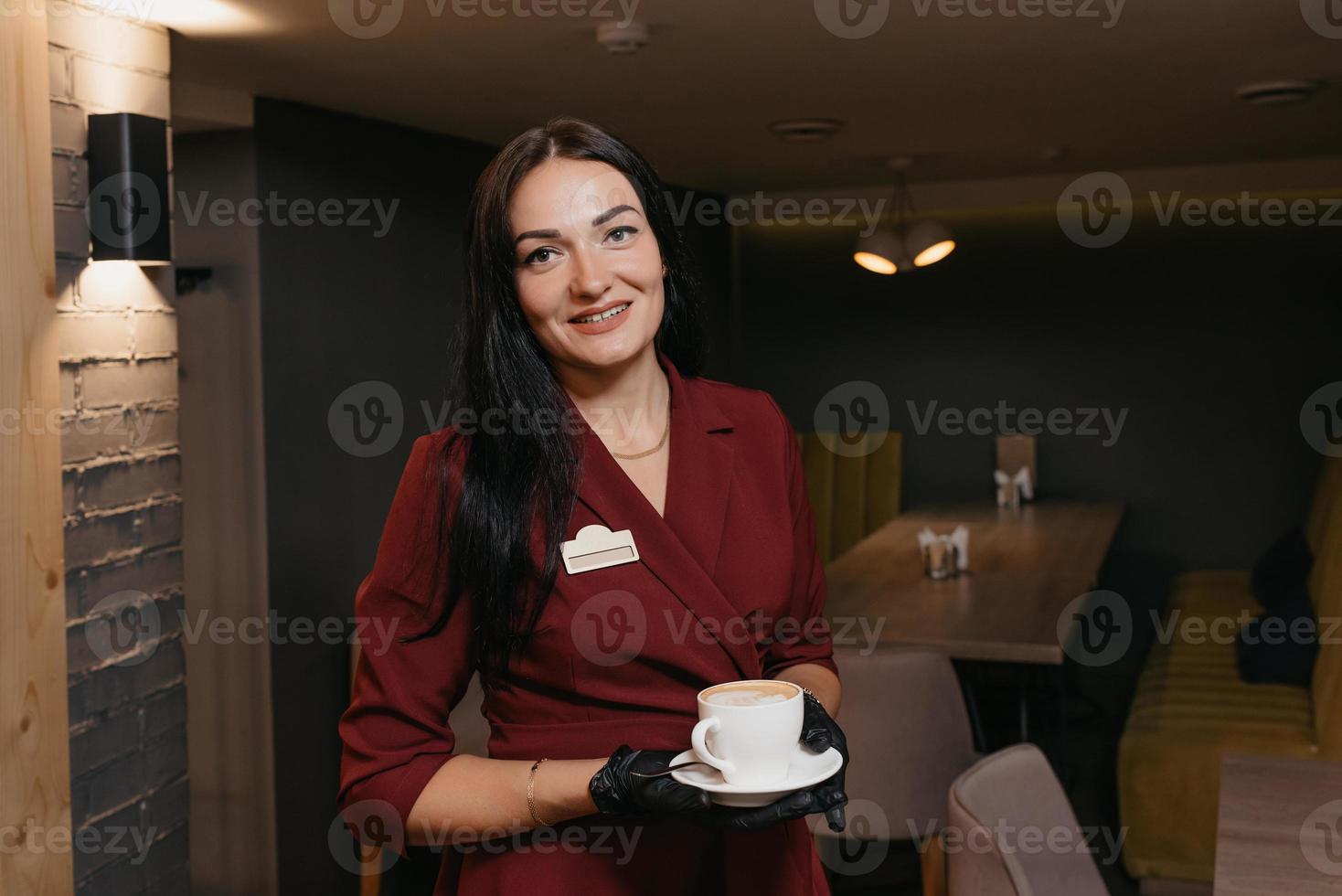 Ein freundlicher Cafébesitzer in einem Rubinkleid wartet auf Kunden foto