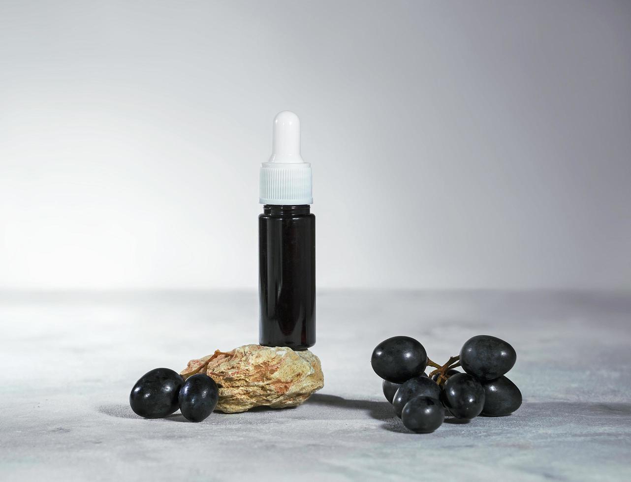 Traubenkernöl in einer Glasflasche mit frischen schwarzen Trauben, reinem ätherischen Hautpflegeöl oder Serum, Schönheitspflege natürliches Bio-Kosmetikkonzept foto
