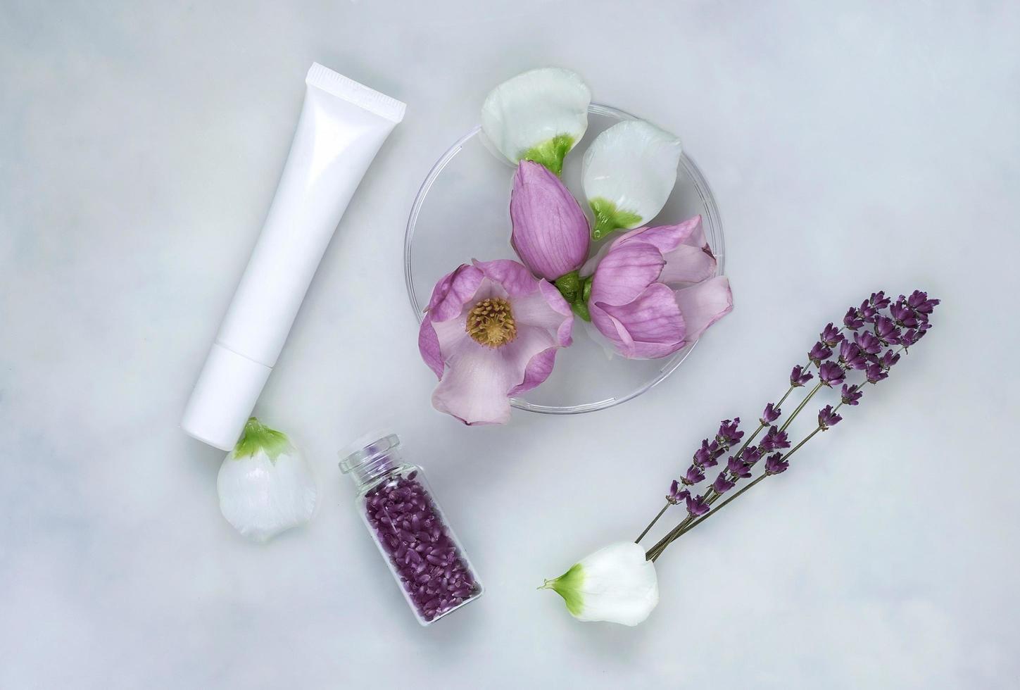 Kräutermedizin mit Magnolienblüten, Petrischalen und Kosmetiktuben, natürlicher Hautpflegehintergrund foto