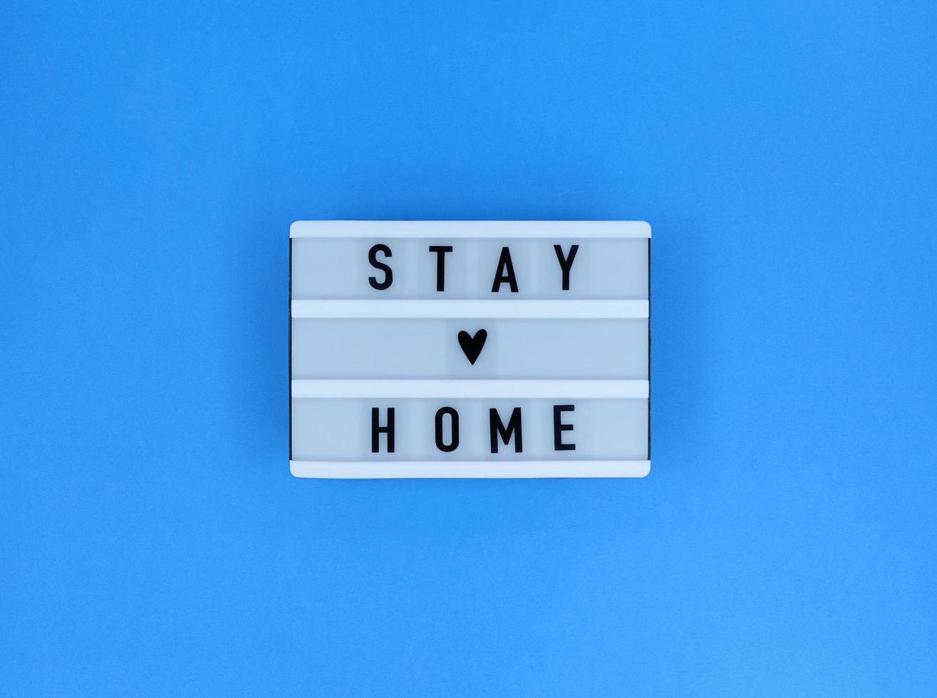 Leuchtkasten mit einem Zitat, das zu Hause bleibt, auf einem blauen Hintergrund foto