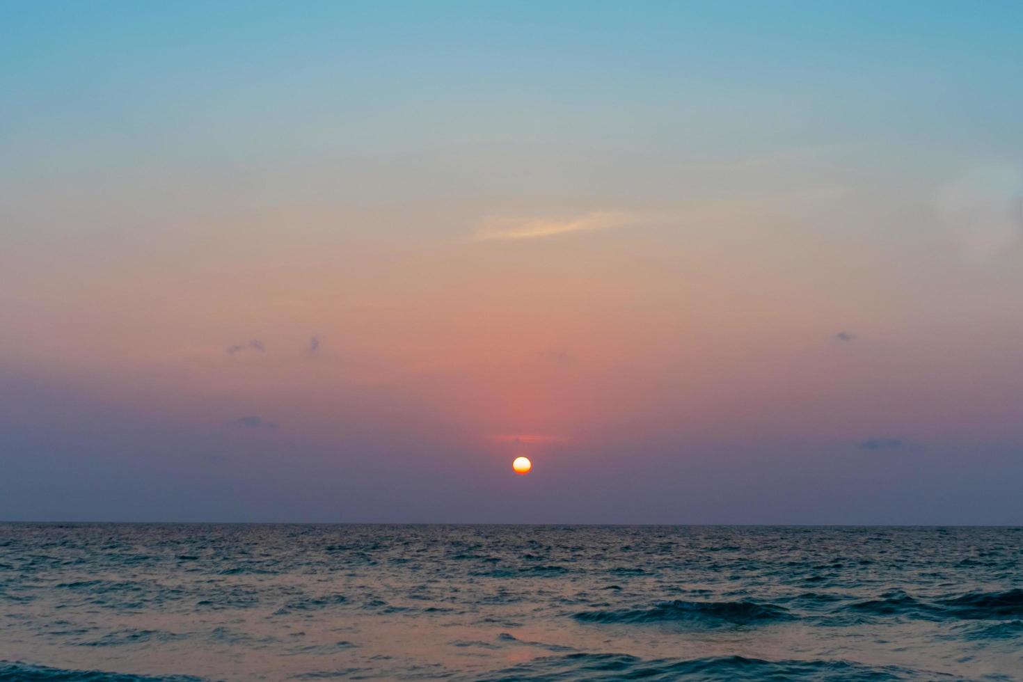 bunte Ozeanmeerwellen während eines Sonnenaufgangs oder Sonnenuntergangs mit der Sonne im Hintergrund foto