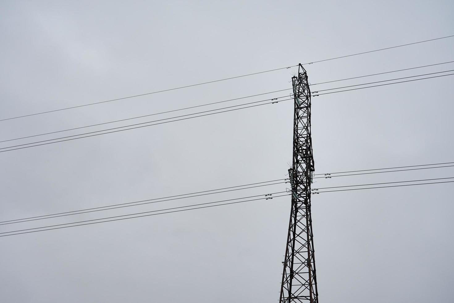 Hochspannungsdrahtturm gegen einen grauen bewölkten Himmel foto