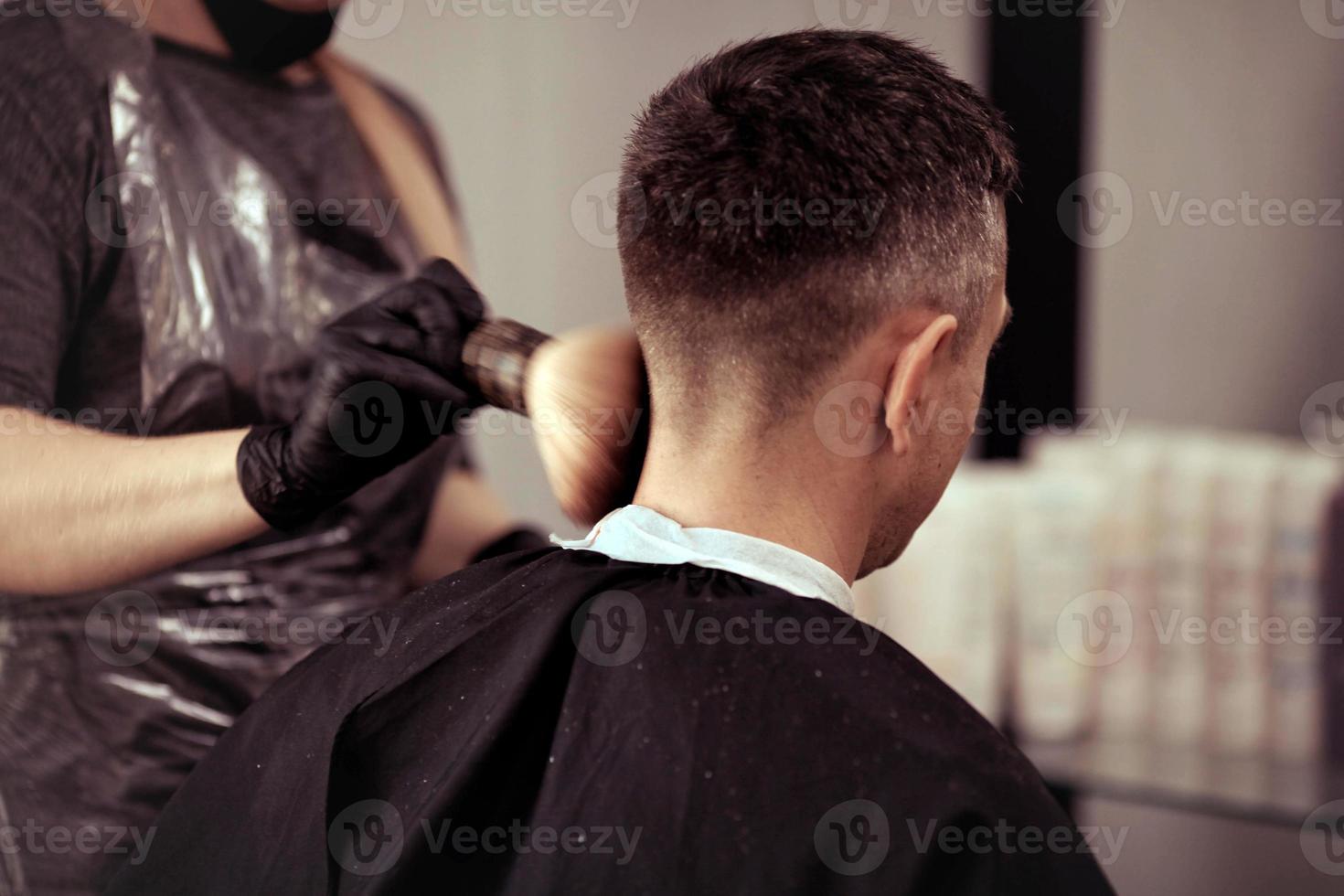 ein Friseur mit Sicherheit Maße zum COVID-19, hält Schere im seine Hände und schneidet ein Mann, Schneiden Haar mit Gummi Handschuhe foto