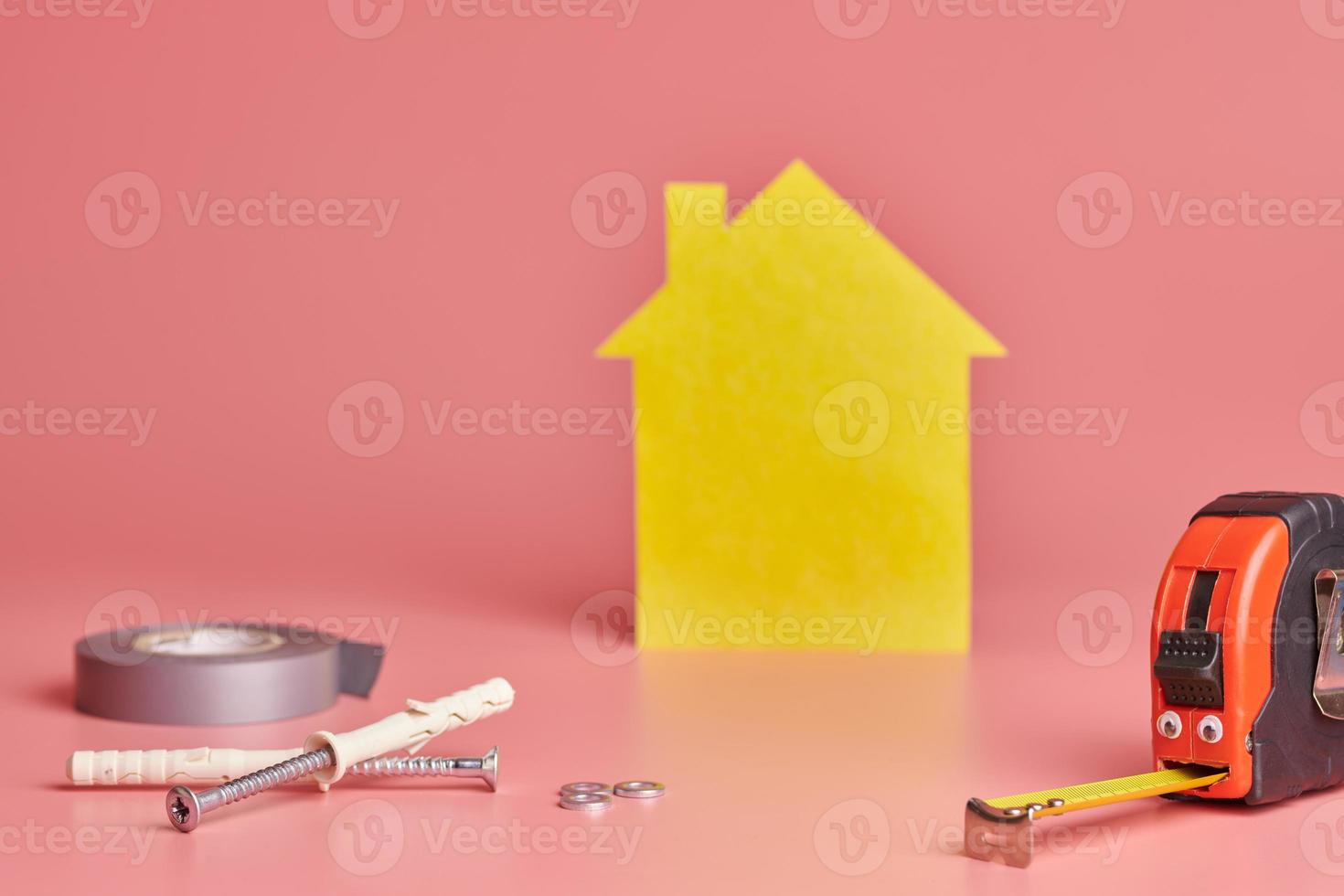 Metallbandmaß lustiges Konzept. Hausrenovierung. hausreparatur und neu gestaltetes konzept. gelbe hausförmige figur auf rosa hintergrund. foto