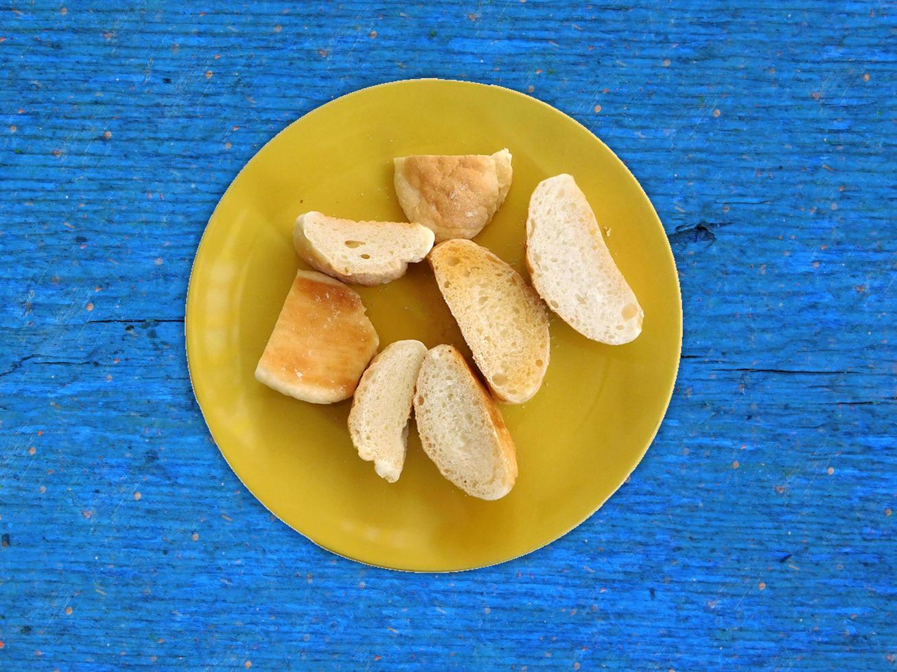 geschnittenes Brot auf einem gelben Teller auf hölzernem Tischhintergrund foto
