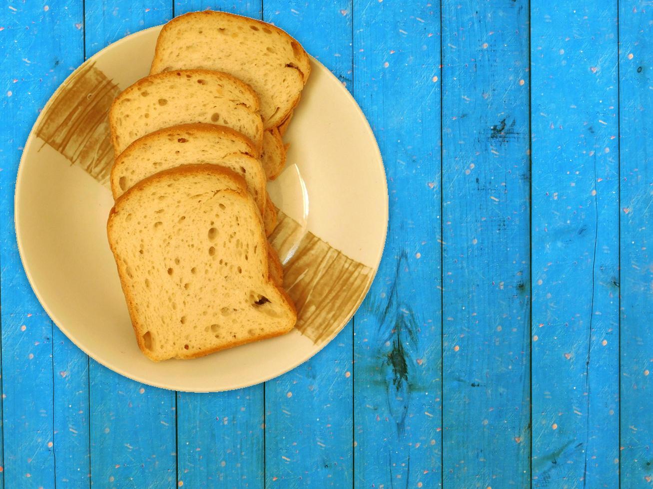 geschnittenes Brot auf einer Keramikplatte auf einem hölzernen Tischhintergrund foto