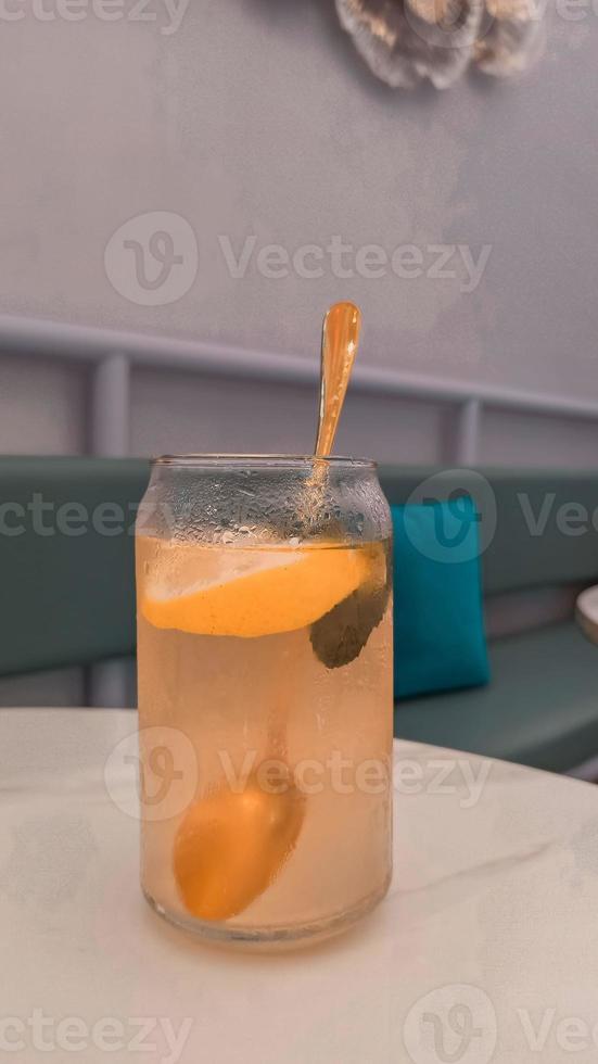 ein Glas von Limonade mit ein Löffel im es und ein Glas mit ein Blau Kissen auf das Tabelle foto