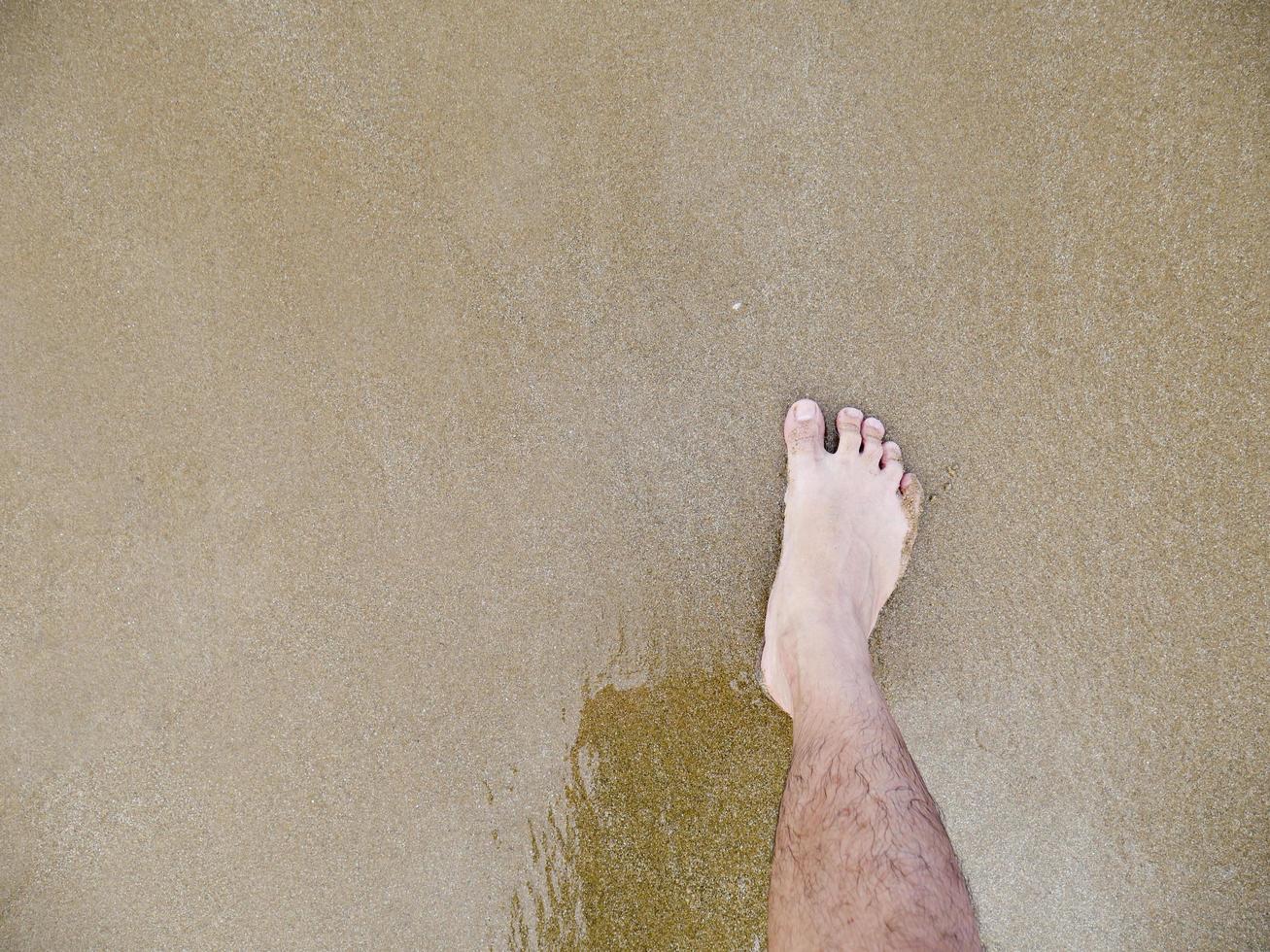 männlicher Fuß im Sand foto