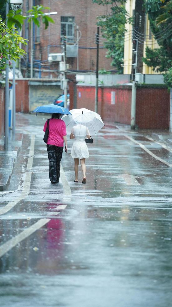 Guangzhou Stadt, China, 2022 - - das Menschen Gehen auf das Straße mit das Regenschirm im das regnerisch Tag foto