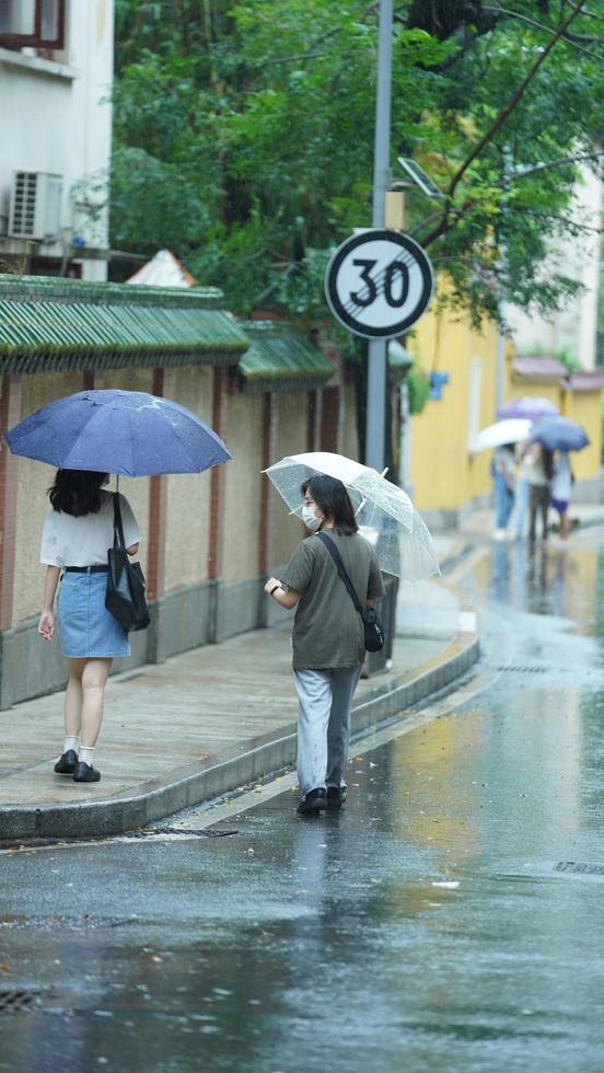 Guangzhou Stadt, China, 2022 - - das Menschen Gehen auf das Straße mit das Regenschirm im das regnerisch Tag foto