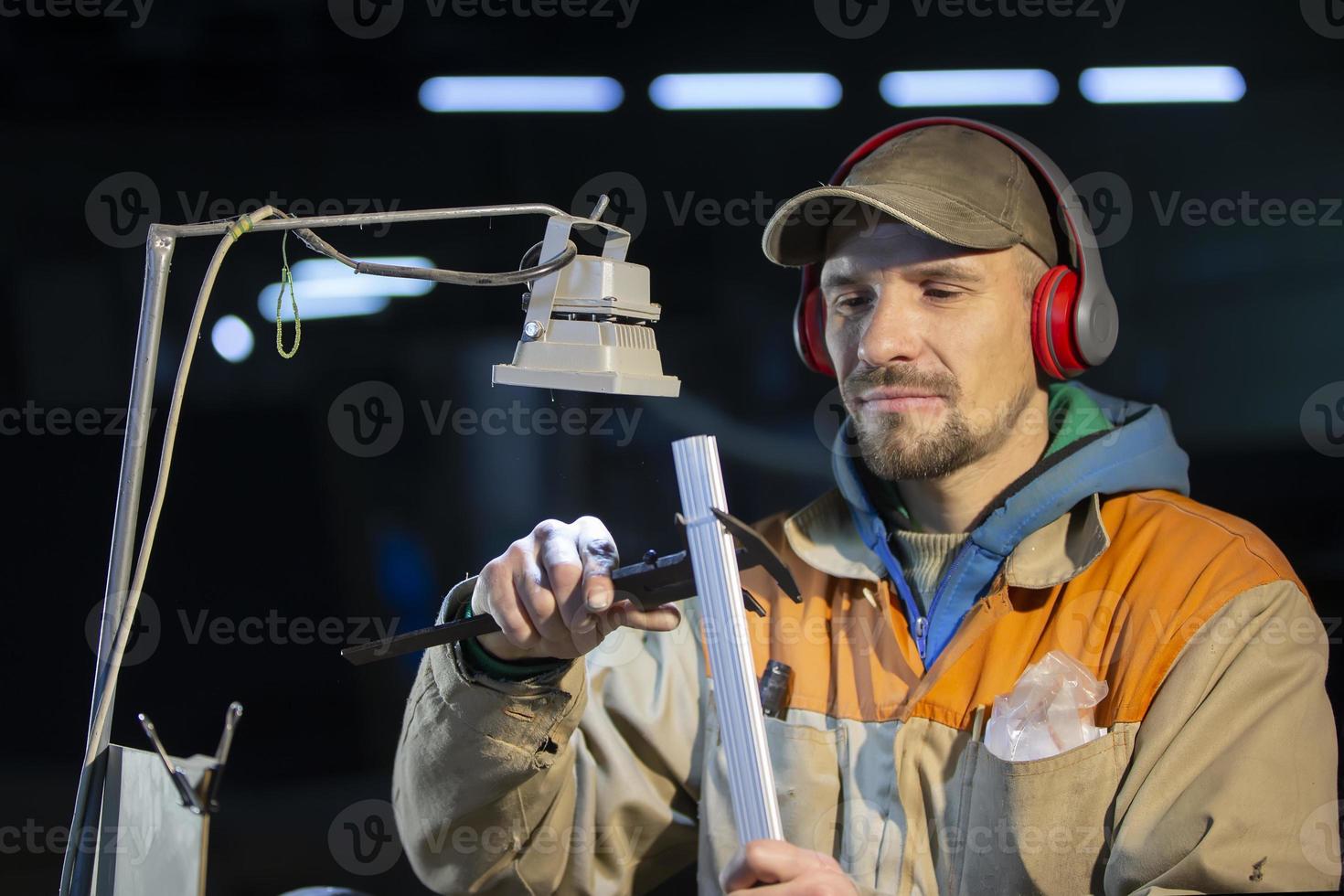 ein Arbeiter im das Möbel Industrie Maße ein Metall Profil mit ein Bremssattel. foto