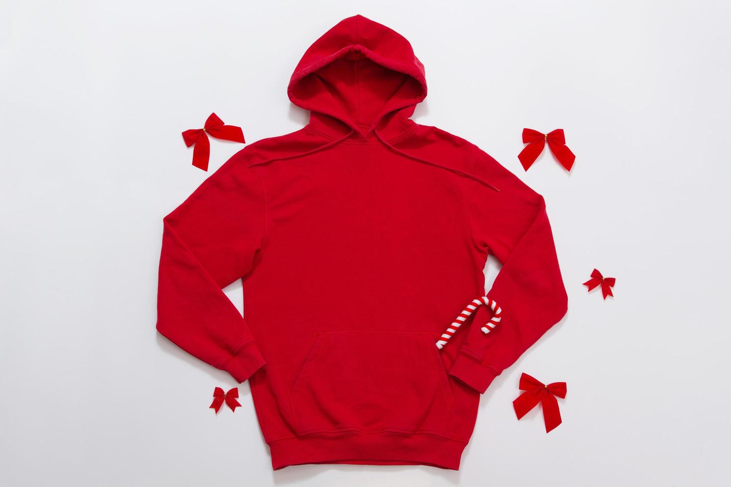 schließen sie herauf roten leeren schablonen-hoodie-kopienraum. weihnachtsferienkonzept. draufsicht mockup hoodie, schal, hut. roter feiertagsdekorationen weißer hintergrund. frohes neues jahr zubehör. selektiver Fokus foto