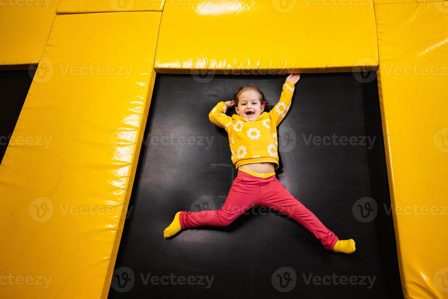 Baby Mädchen Kind Lügen auf Trampolin beim Spielplatz Park. Kind im Bewegung während aktiv Unterhaltungen. foto