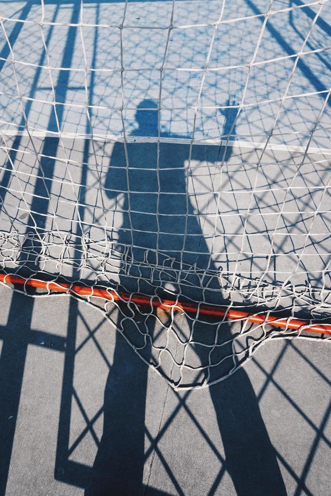 Männerschatten mit einem Seilnetz auf dem Boden foto