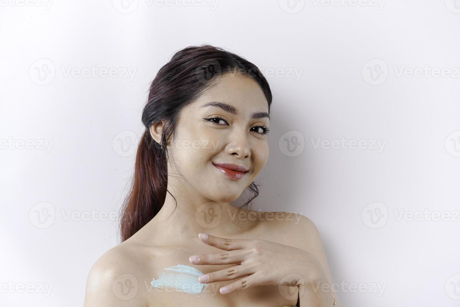 Haut Pflege Produkte Konzept. asiatisch Frau bewirbt sich feuchtigkeitsspendend Lotion auf Körper nach Dusche, Stehen eingewickelt im Handtuch, abgeschnitten Bild foto