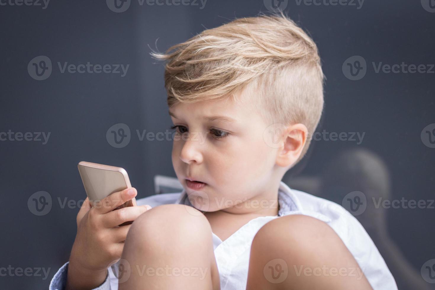 kleines Kind beobachtet etwas auf dem Smartphone foto