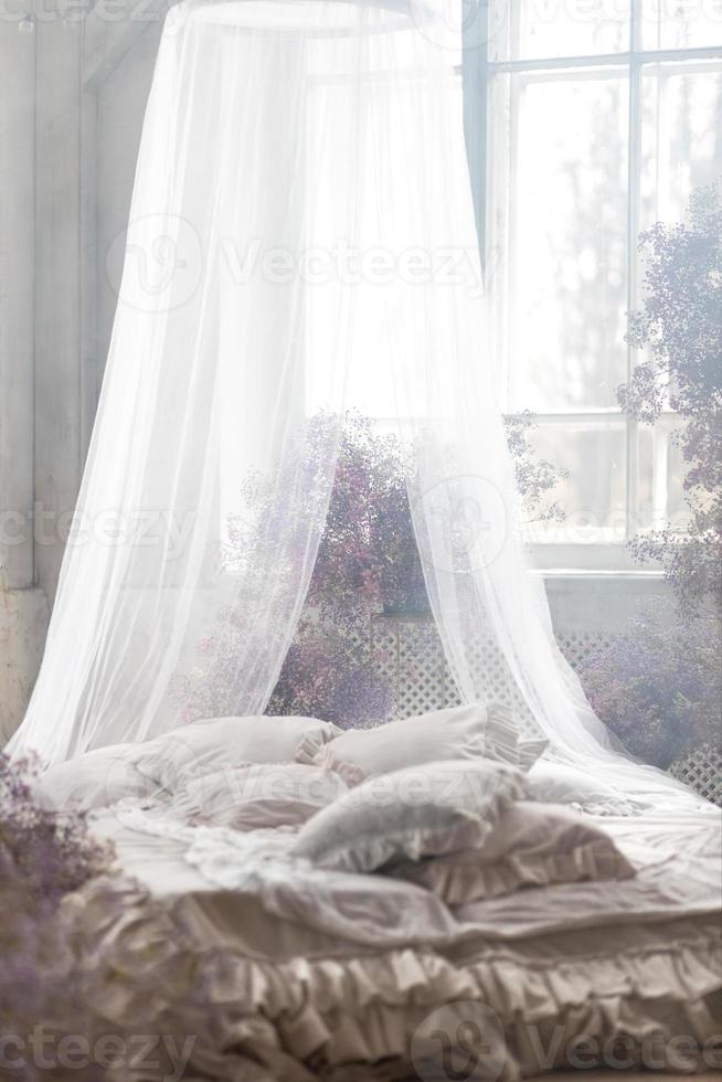 ein Bett im ein hell Schlafzimmer im Pastell- Farben im Boho Stil, das Trend Farbe von 2023. das Zimmer ist dekoriert mit lila und Rosa Gypsophila Blumen, Jahrgang Dekor im das Zimmer im retro Dachgeschoss Stil. foto