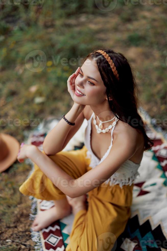 jung schön Hippie Frau Sitzung auf das Boden im Natur im das fallen im Öko Kleidung im das Sonnenuntergang Licht, ein Lebensstil von Reise und Harmonie mit das Welt foto