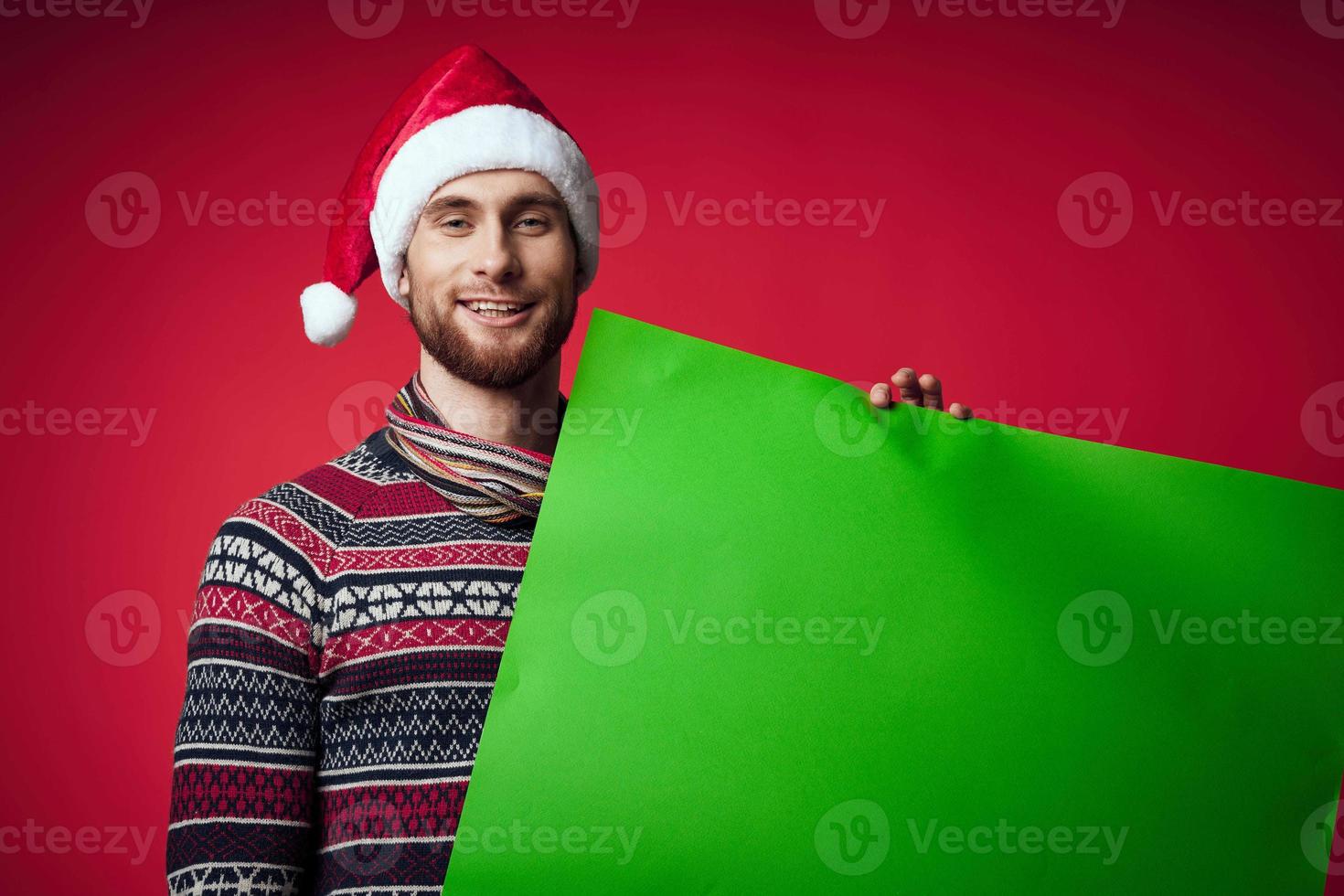 heiter Mann im ein Weihnachten Hut mit Grün Attrappe, Lehrmodell, Simulation rot Hintergrund foto