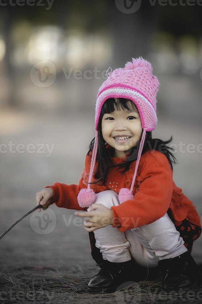 Porträt von süß asiatisch wenig Mädchen tragen Winter Kleider beim das Wald von das parken, thailand Menschen Pose zum nehmen ein Bild, glücklich Zeit foto