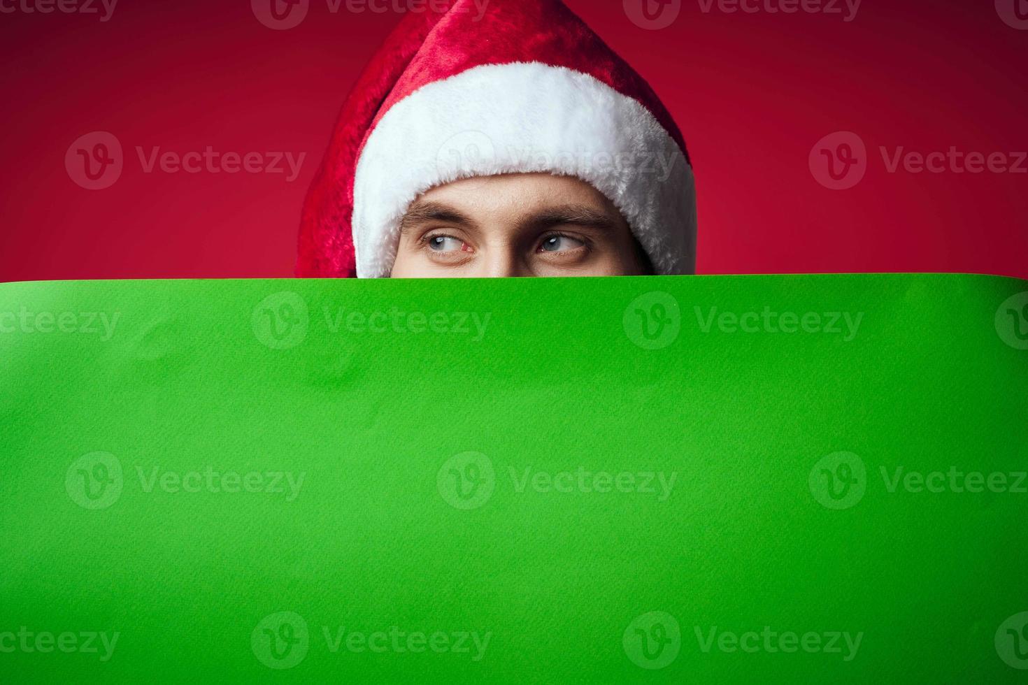 gut aussehend Mann im ein Santa Hut halten ein Banner Urlaub Studio posieren foto