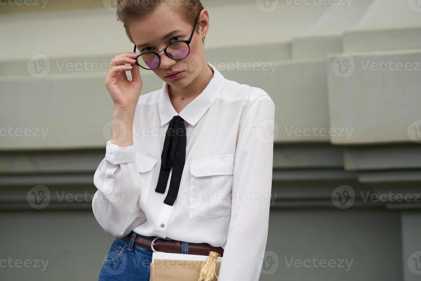 kurz behaart Frau mit Brille Gehen um das Stadt mit ein Buch Kommunikation foto