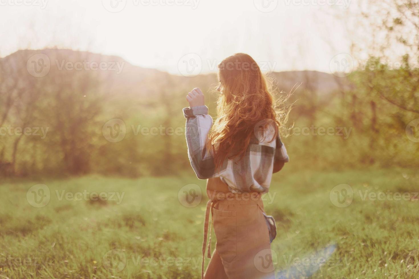 ein Frau Laufen durch ein Feld auf ein Sommer- Tag mit lange fließend Haar im das Strahlen von das Rahmen Sonne. das Konzept von Freiheit und Harmonie mit Natur foto